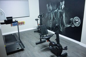 Stay fit on the go with a fully equipped gym featuring a stationary bike, elliptical trainer, and dumbbells.