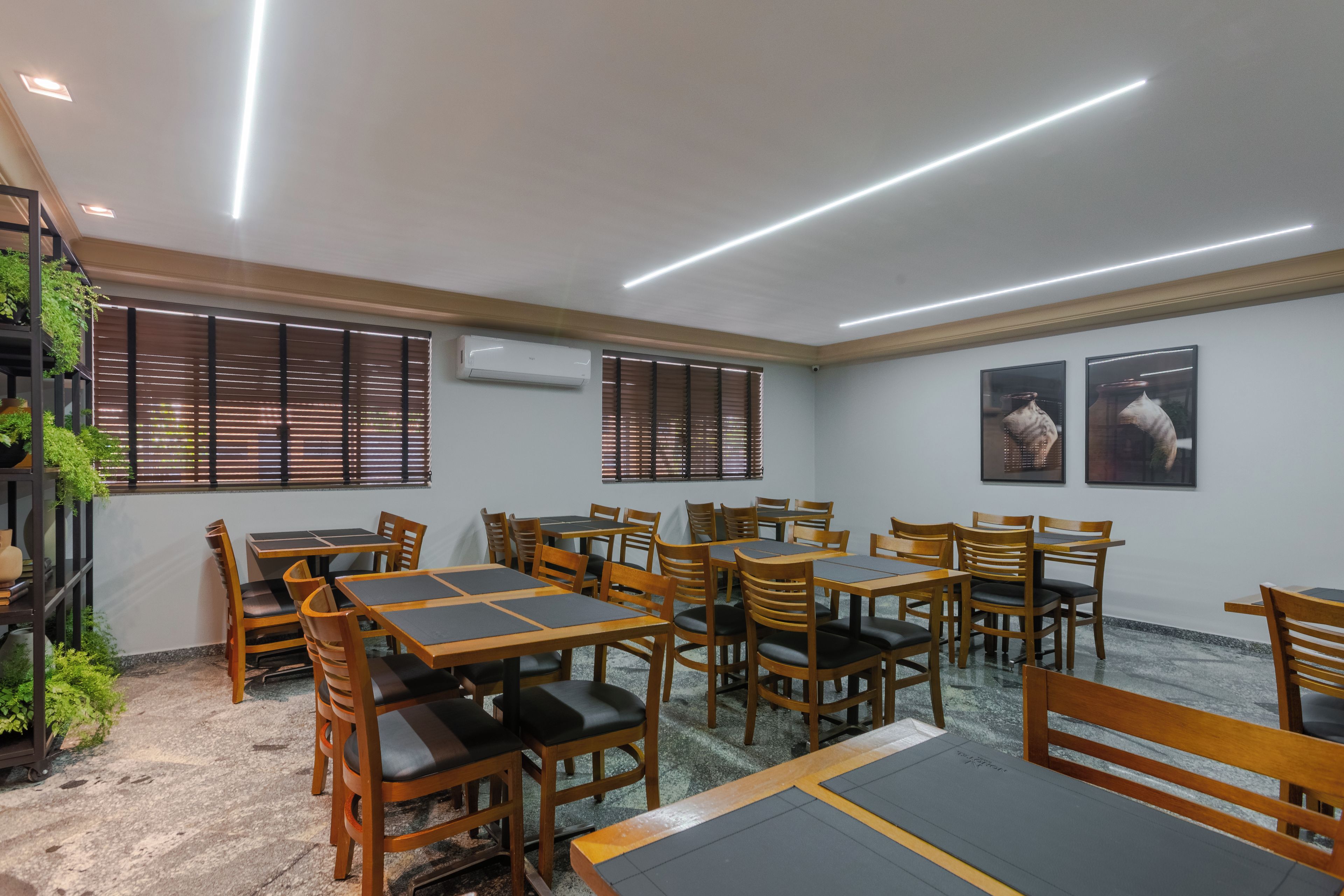 A conference room with multiple tables and chairs, air conditioning units, and windows with blinds.