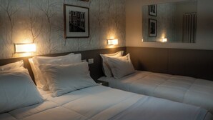 Habitación de hotel con dos camas, una pared de mármol y cuadros enmarcados.