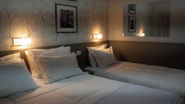 Habitación de hotel con dos camas, una pared de mármol y cuadros enmarcados.