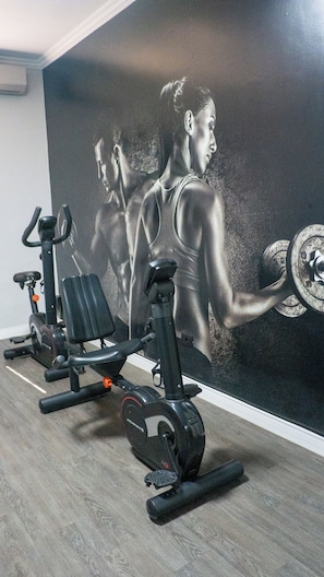 Un gimnasio con equipo de ejercicio y un gran mural de una figura musculosa.