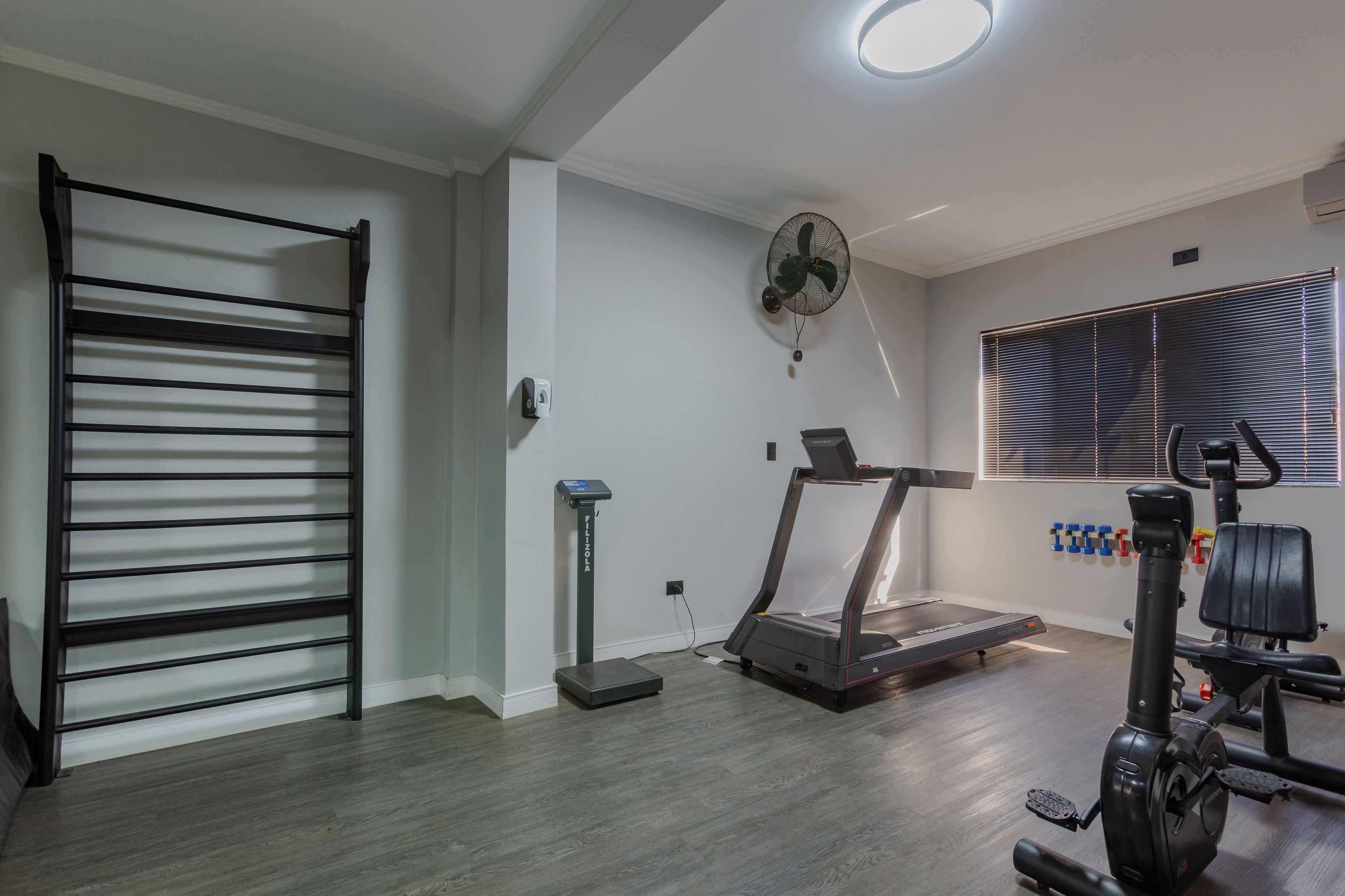 Un gimnasio con cinta de correr, bicicleta estática y pesas.