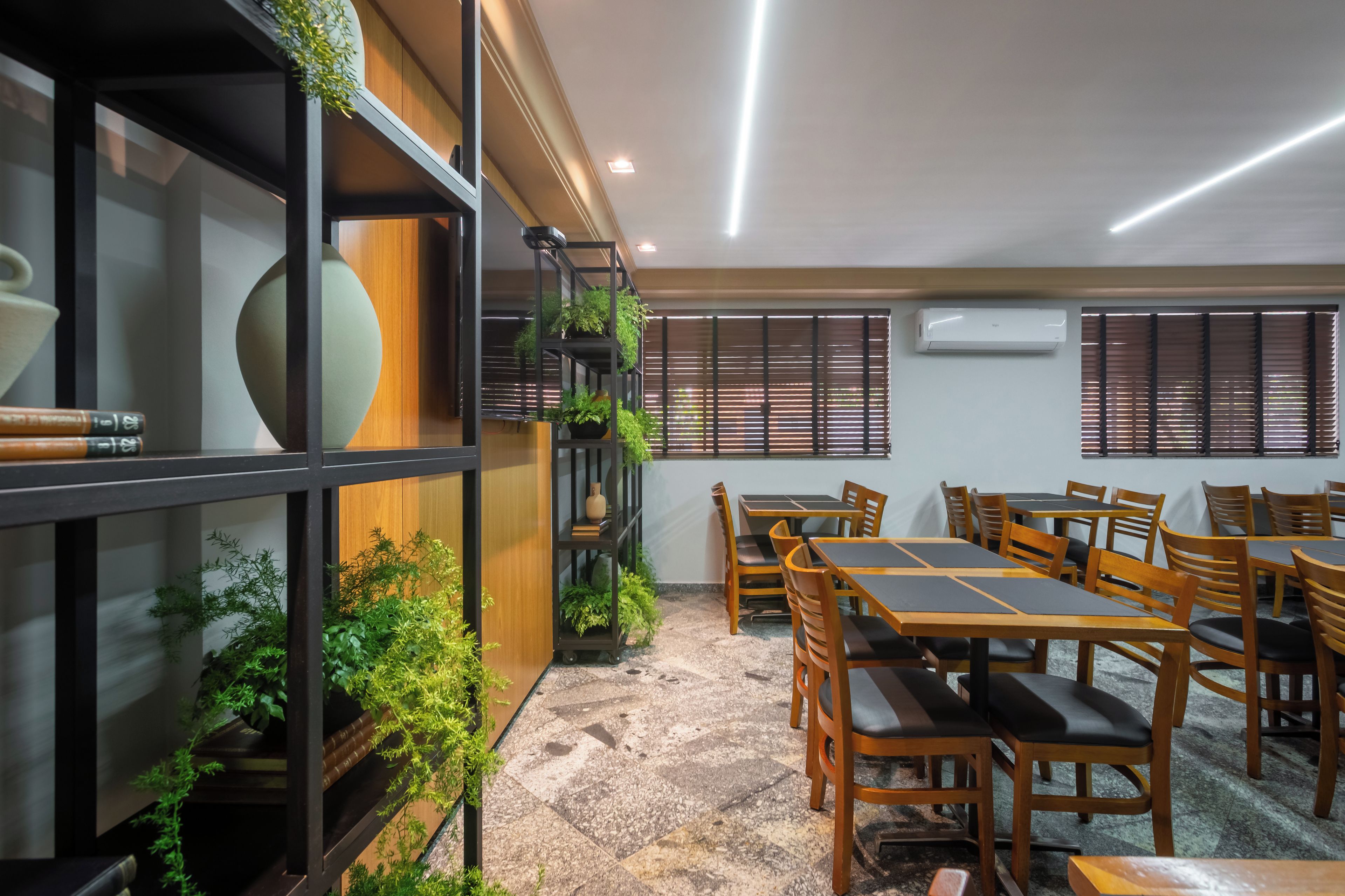 A conference room with a round table, chairs, and a bookshelf with plants.