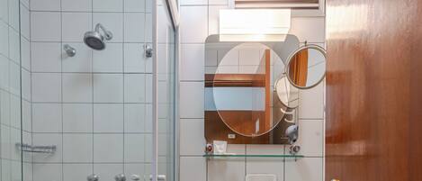 Un baño con ducha de vidrio, un lavabo con encimera de mármol y una puerta de madera.