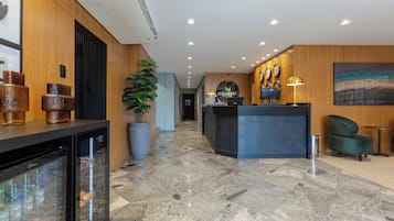 Un hall d’hôtel avec un comptoir d’accueil, une grande plante en pot et une horloge murale.