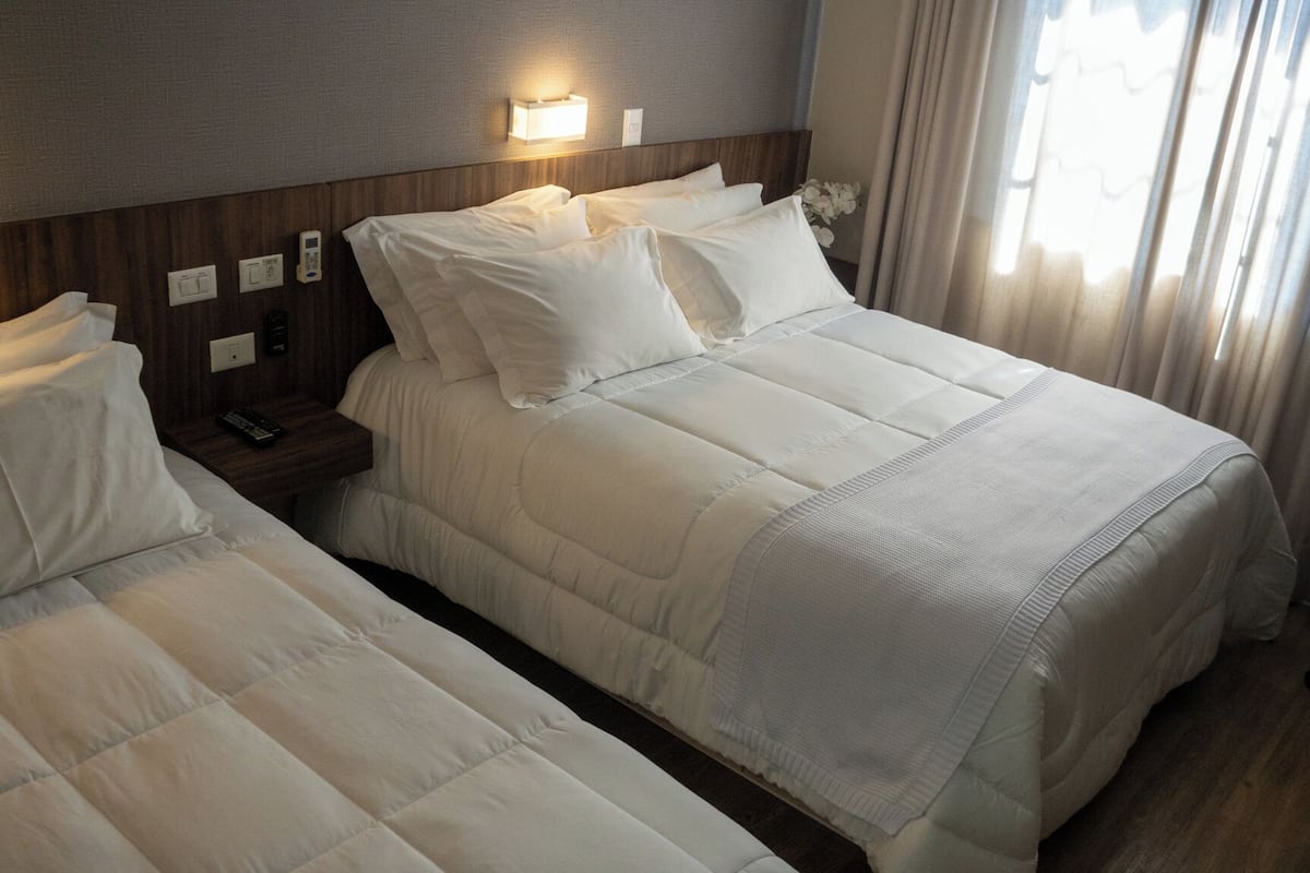 Habitación de hotel con dos camas, una mesita de noche con teléfono, lámpara y una silla.