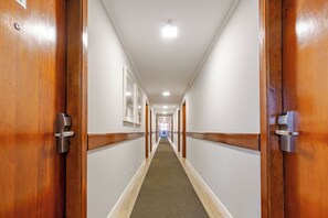 Ein Hotelkorridor mit Holztüren, weißen Wänden und Teppichboden.