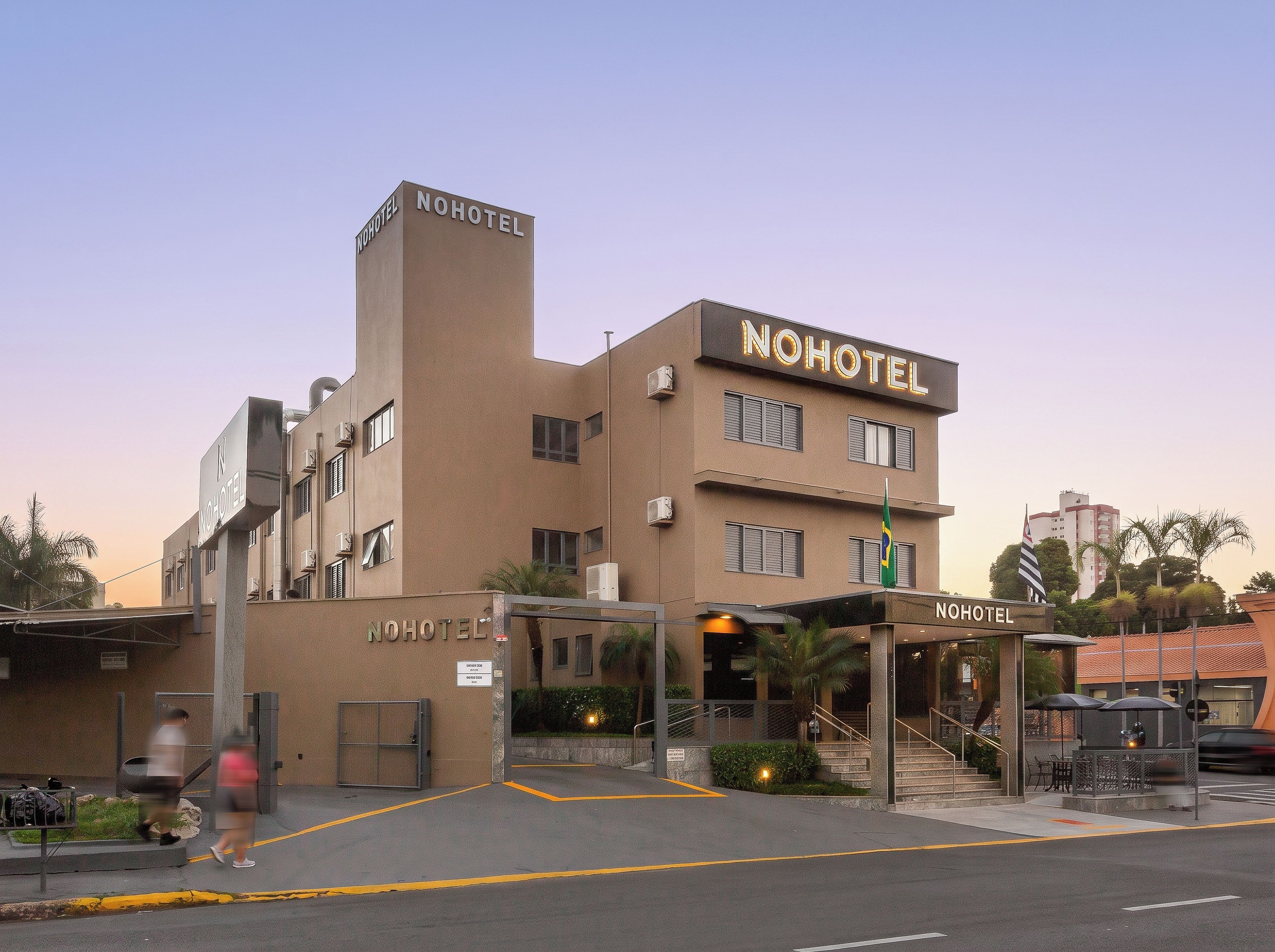 A hotel with a prominent sign, a covered entrance, and a flag.