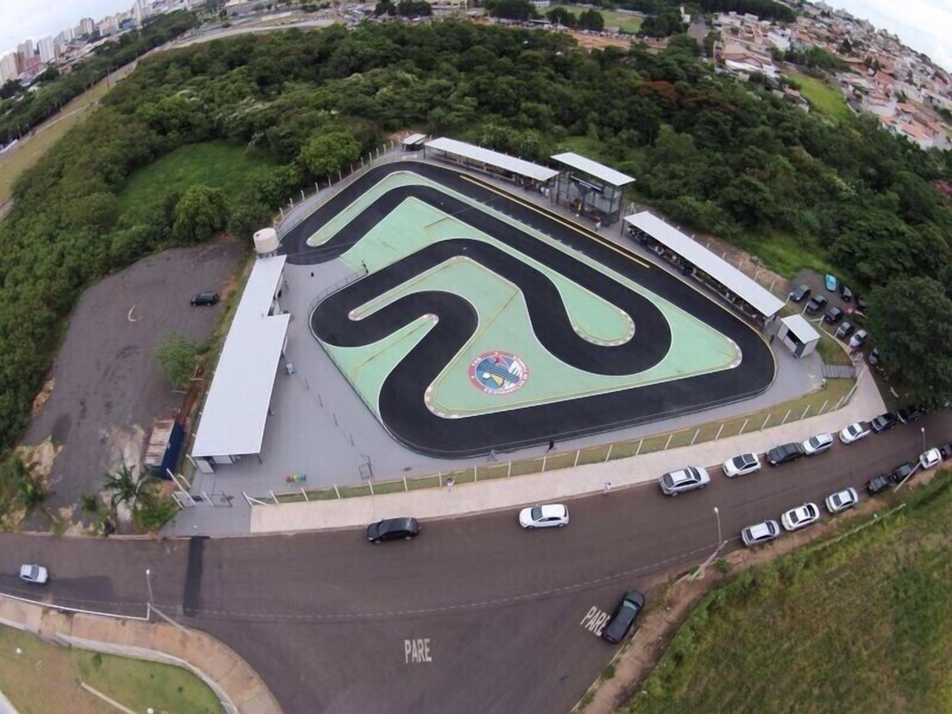 Vista aérea de uma pista de corrida com área de estacionamento e arquibancadas.