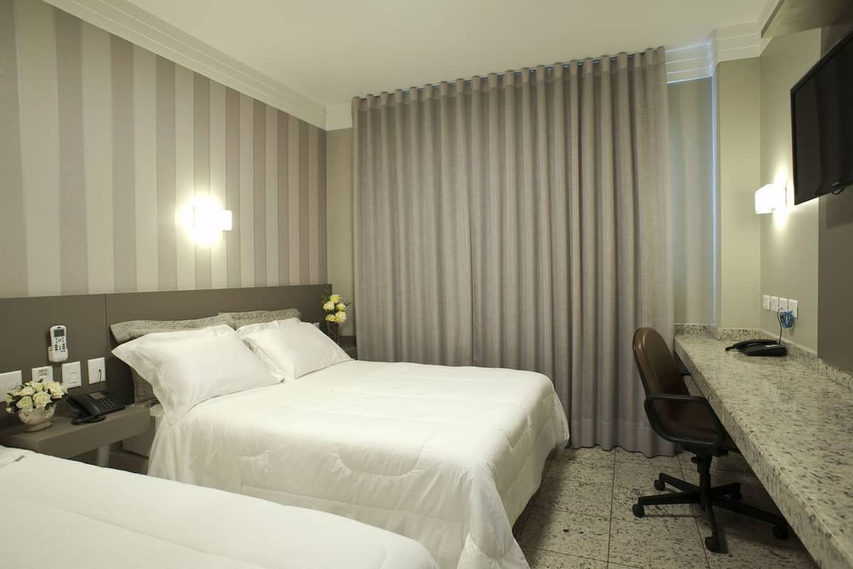 Een hotelkamer met twee bedden, een bureau, een stoel, een telefoon en een televisie.