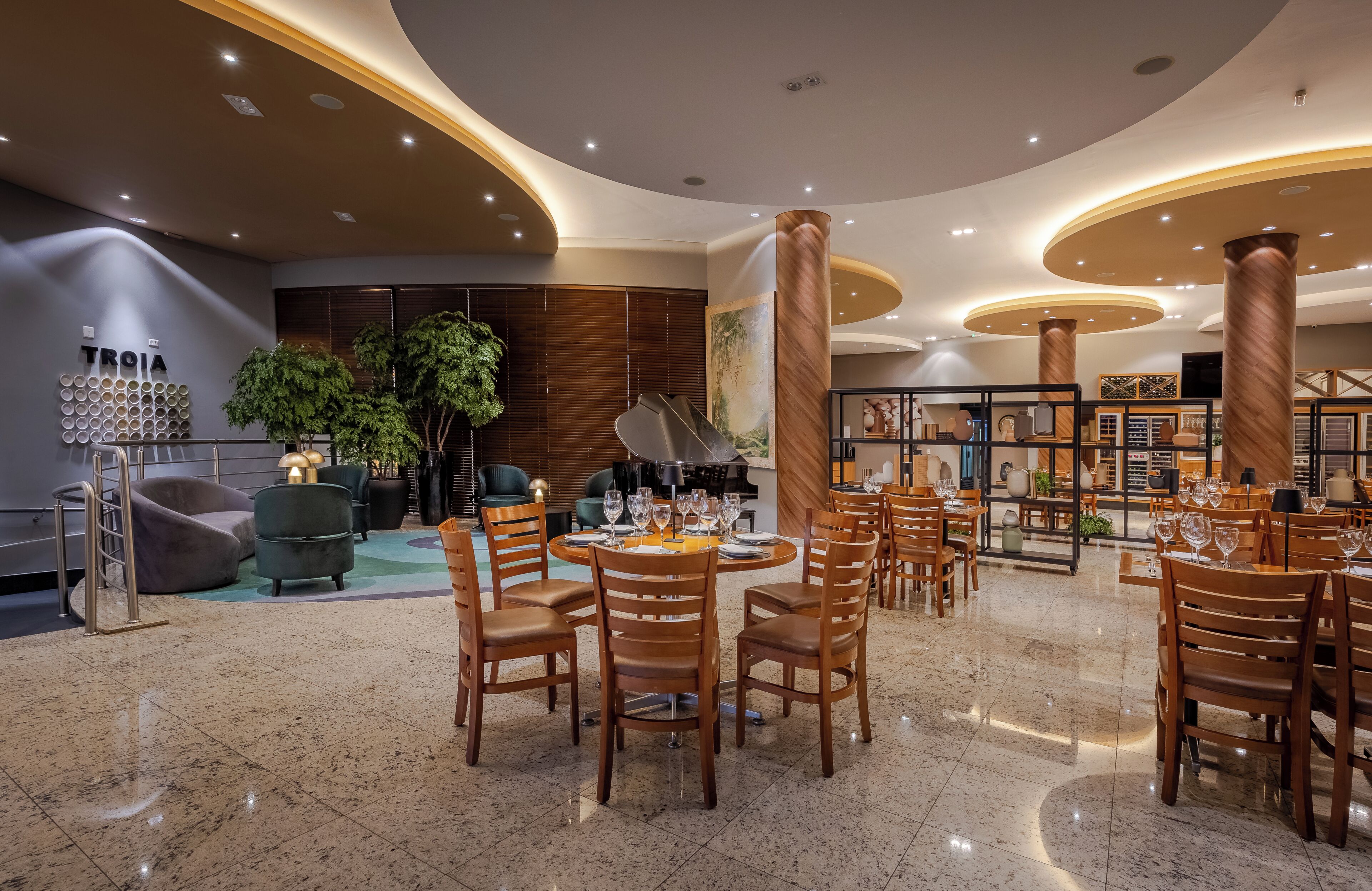 A modern restaurant with round tables, wooden chairs, and a central piano.