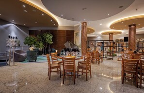 Un restaurante moderno con mesas redondas, sillas de madera y un piano en el centro.