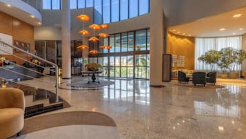 A spacious lobby with a high ceiling, a central seating area, and a staircase leading to an upper level.