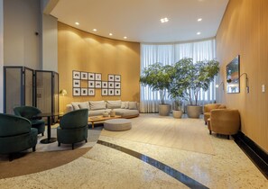 Een moderne woonkamer met een bank, fauteuils, een salontafel en een grote potplant.