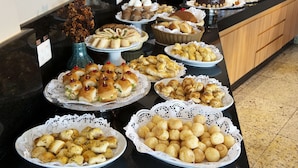 Een buffet met diverse gerechten, waaronder gebak, belegde broodjes en desserts.