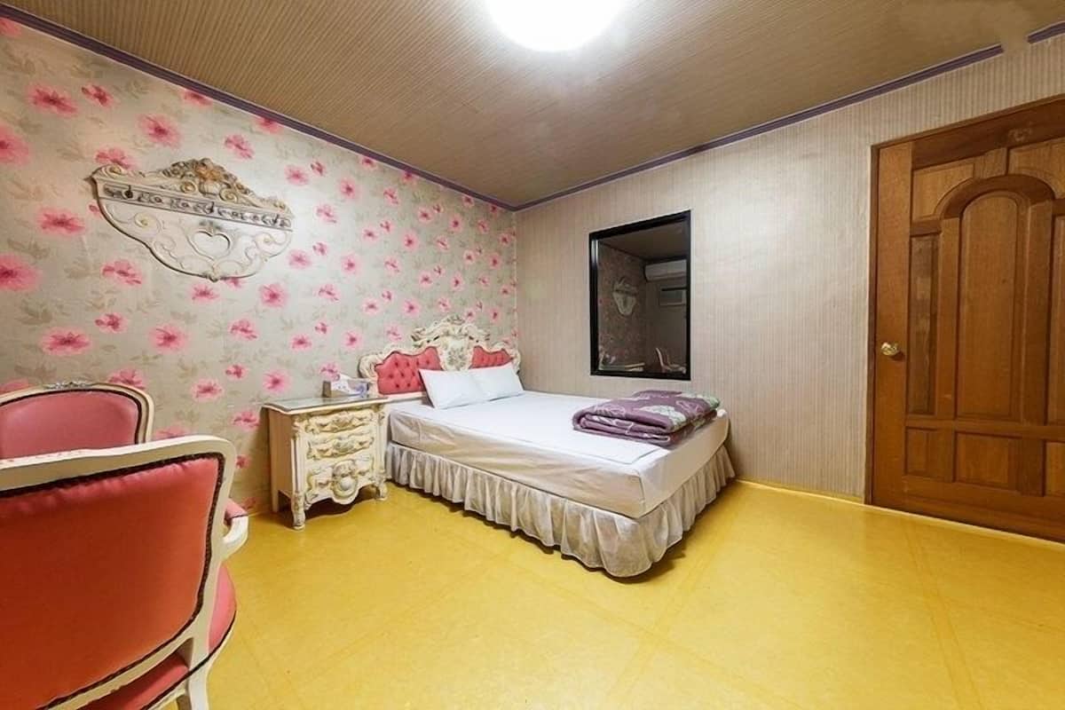 A bedroom with a bed, a dresser, a chair, and a wooden door.