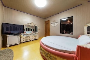 A bedroom with a large bed, a television, a dresser, and a mirror. - Carlsbed Motel (Sokcho)
