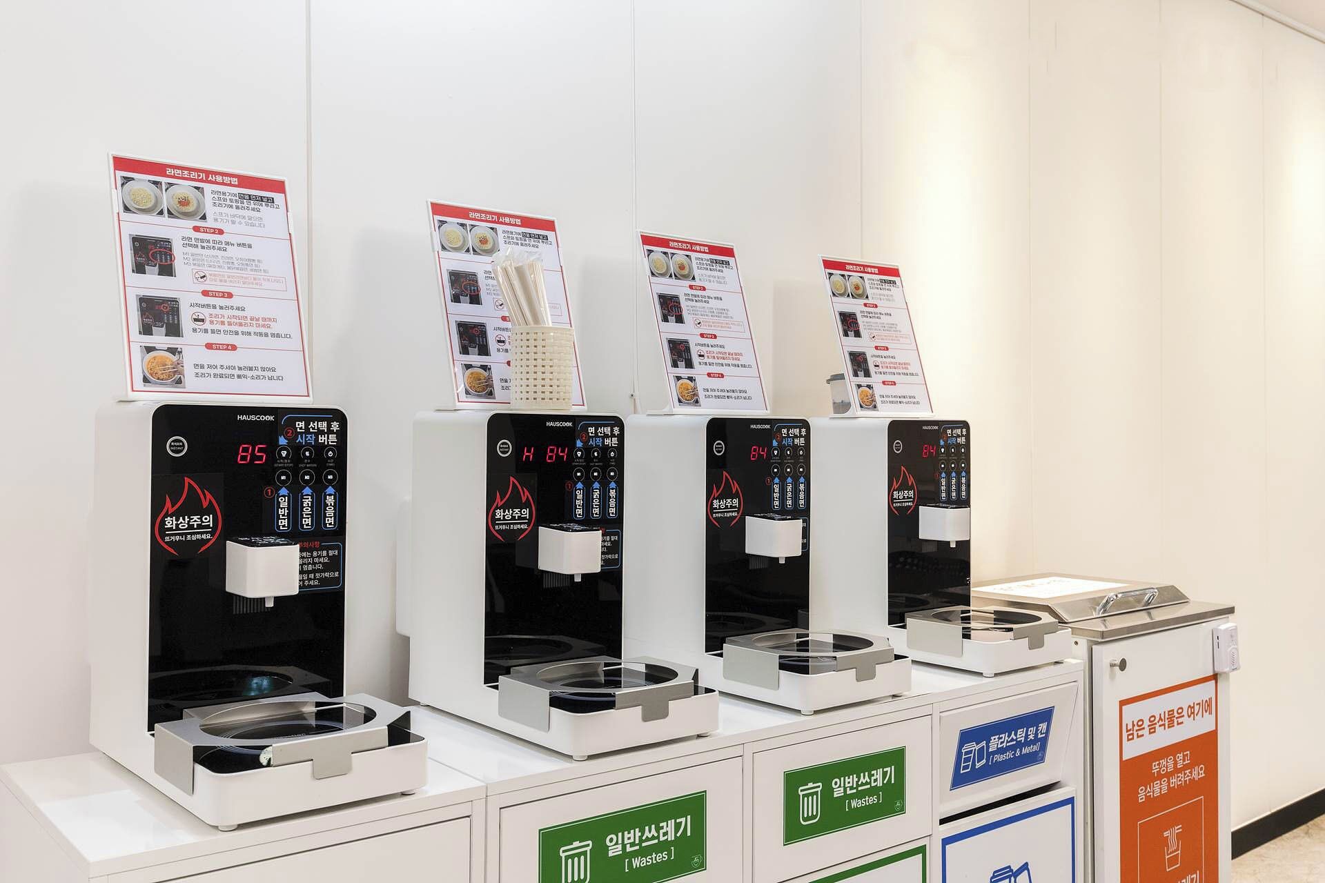 Vier Selbstbedienungsgetränkeautomaten mit digitalen Anzeigen und Beschilderung.