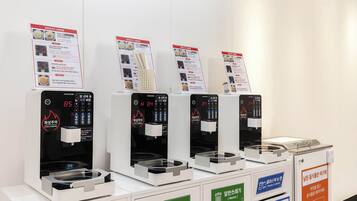 Vier Selbstbedienungsgetränkeautomaten mit digitalen Anzeigen und Beschilderung.