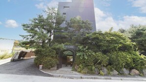 Un bâtiment d’hôtel moderne, avec une enseigne indiquant « La Feliz Hotel » et une entrée de café portant l’inscription « Cafe La Feliz ».