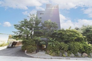 A modern hotel building with a sign reading "La Feliz Hotel" and a cafe entrance labeled "Cafe La Feliz".