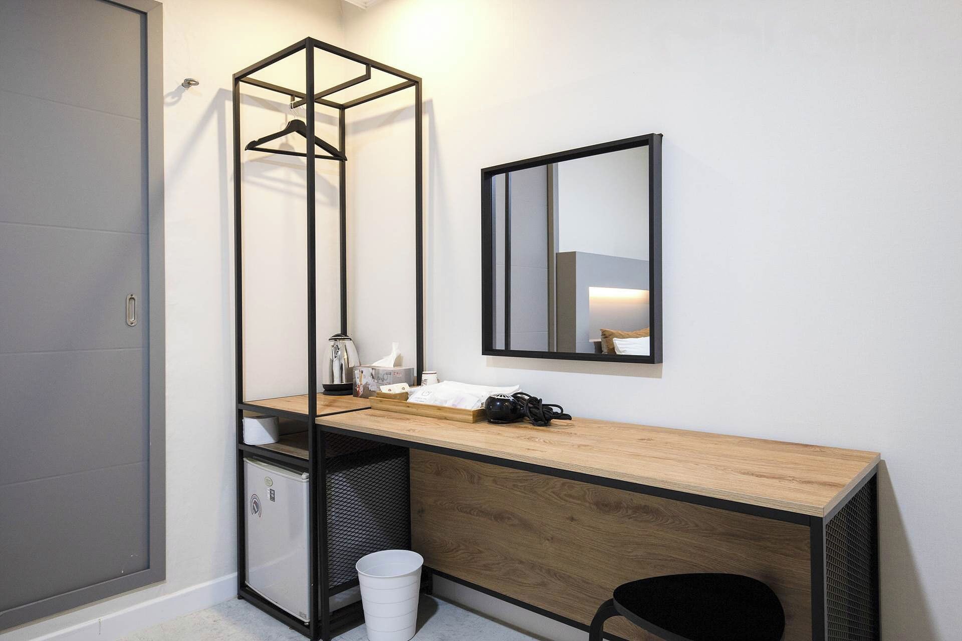 Een compacte badkamer met een houten wastafelmeubel, een handdoekhouder, een spiegel en een klein opbergkastje.