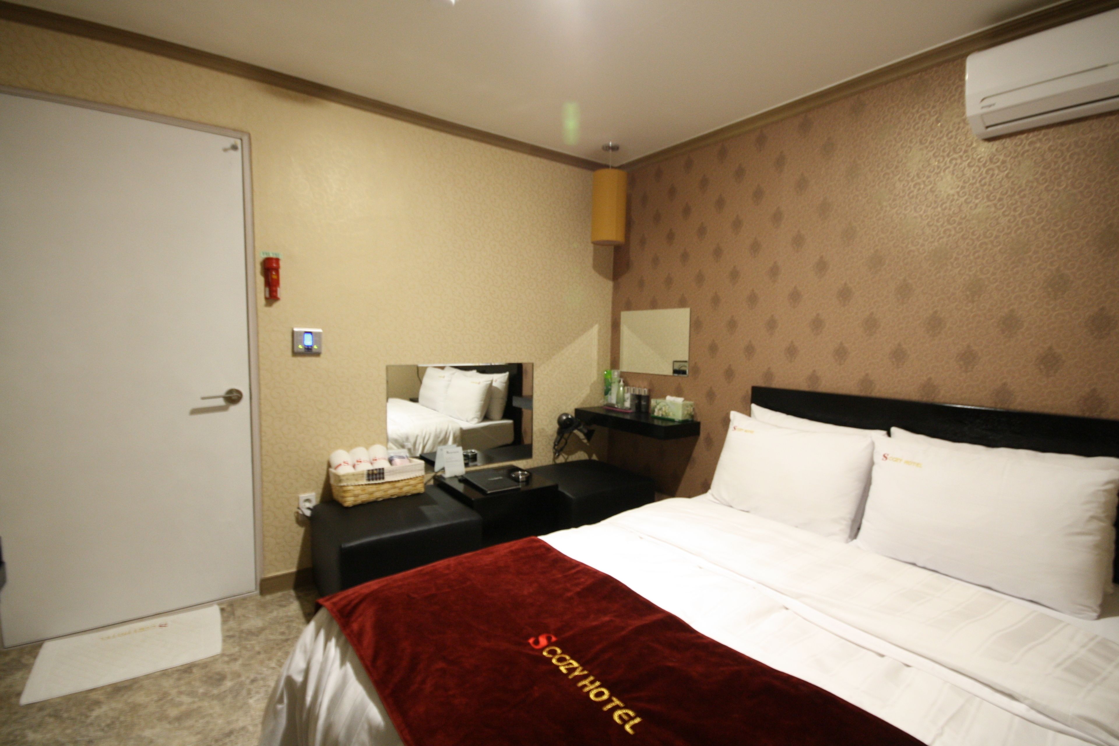 A hotel room with a bed, a nightstand, a dresser, a mirror, and a door.