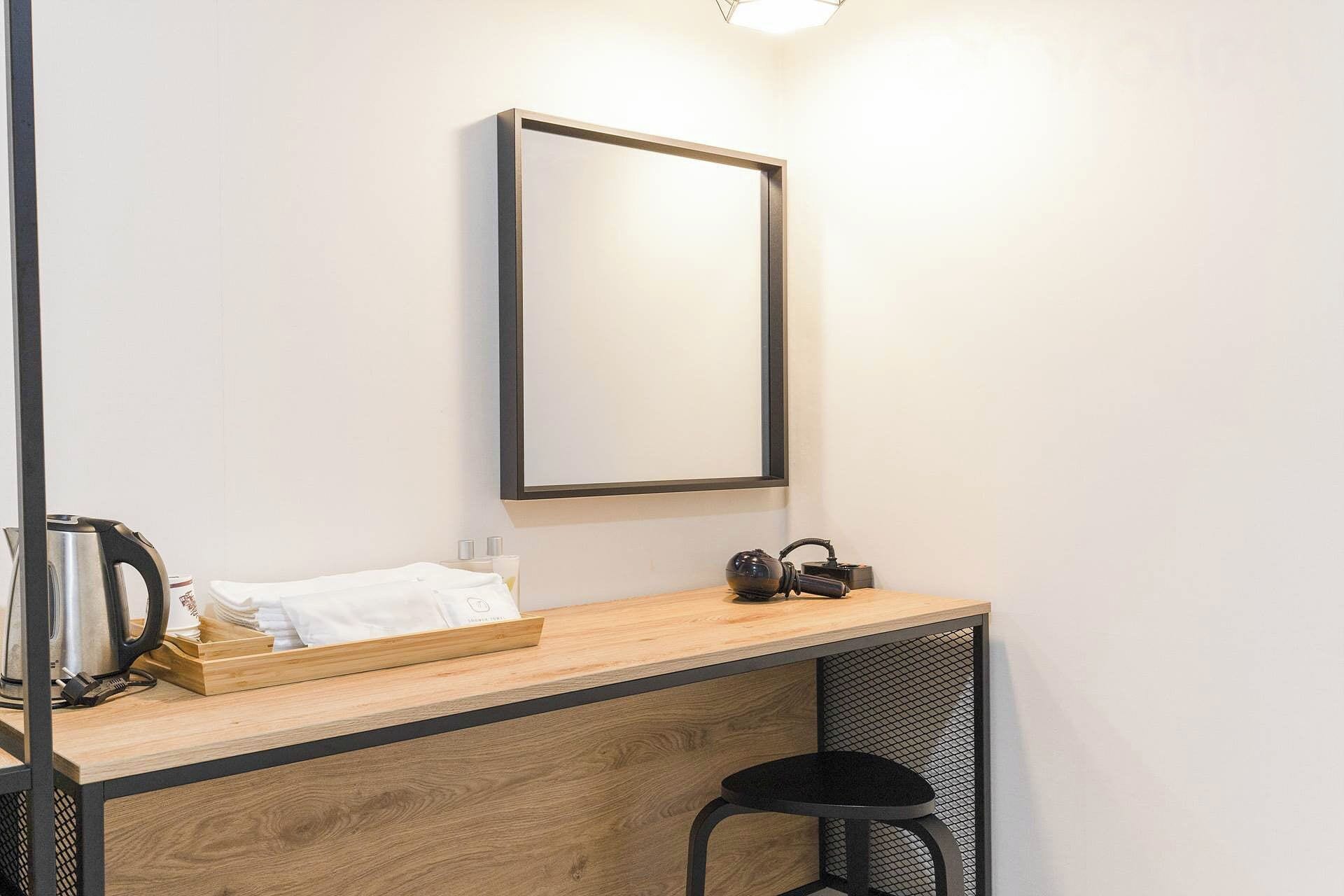 Un baño pequeño y moderno con tocador de madera, espejo, tetera y taburete.