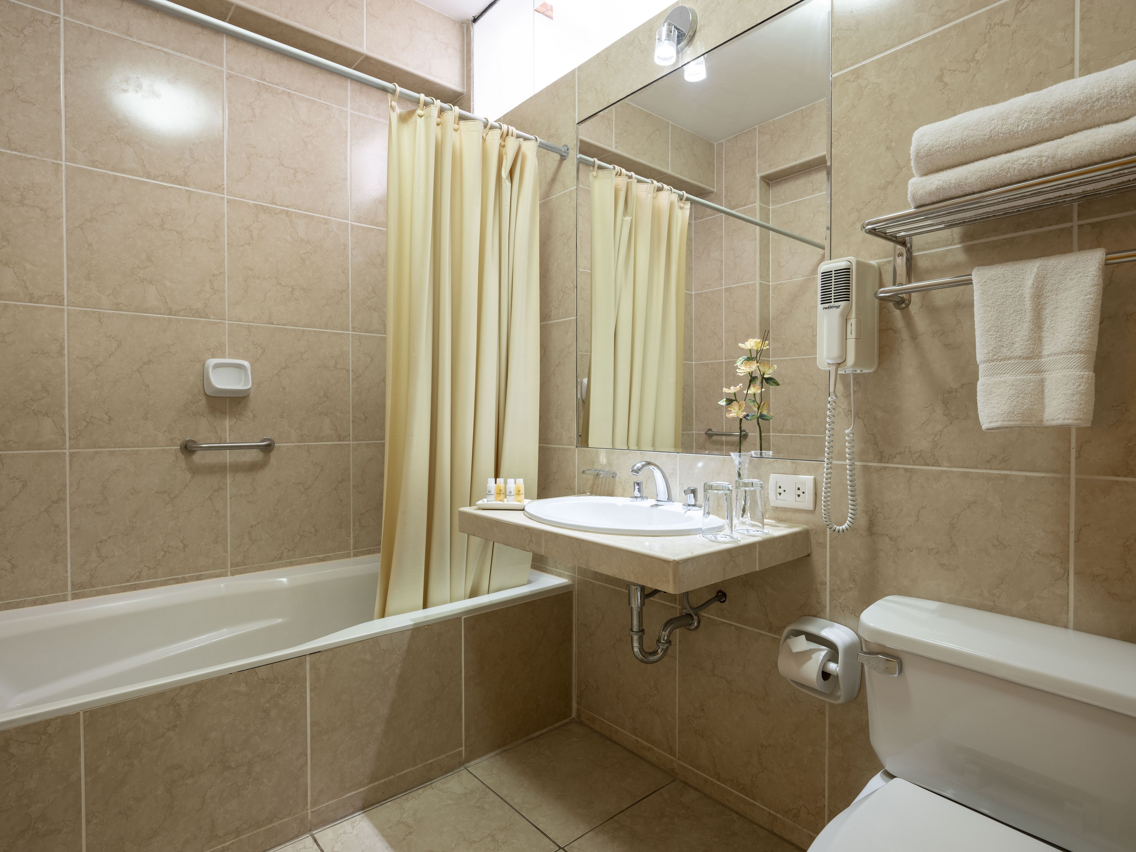 A bathroom with a bathtub, a sink, a toilet, a shower curtain, and a towel rack.