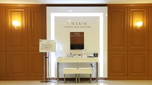 A clinical skin solution display with a white counter, two white benches, and informational posters. - Hotel Skypark Jeju 1 (Jeju City)