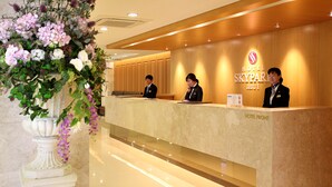A hotel reception desk with a sign reading "HOTEL FRONT" and "SKYPAR SKYPAR JEJUI". - Hotel Skypark Jeju 1 (Jeju City)