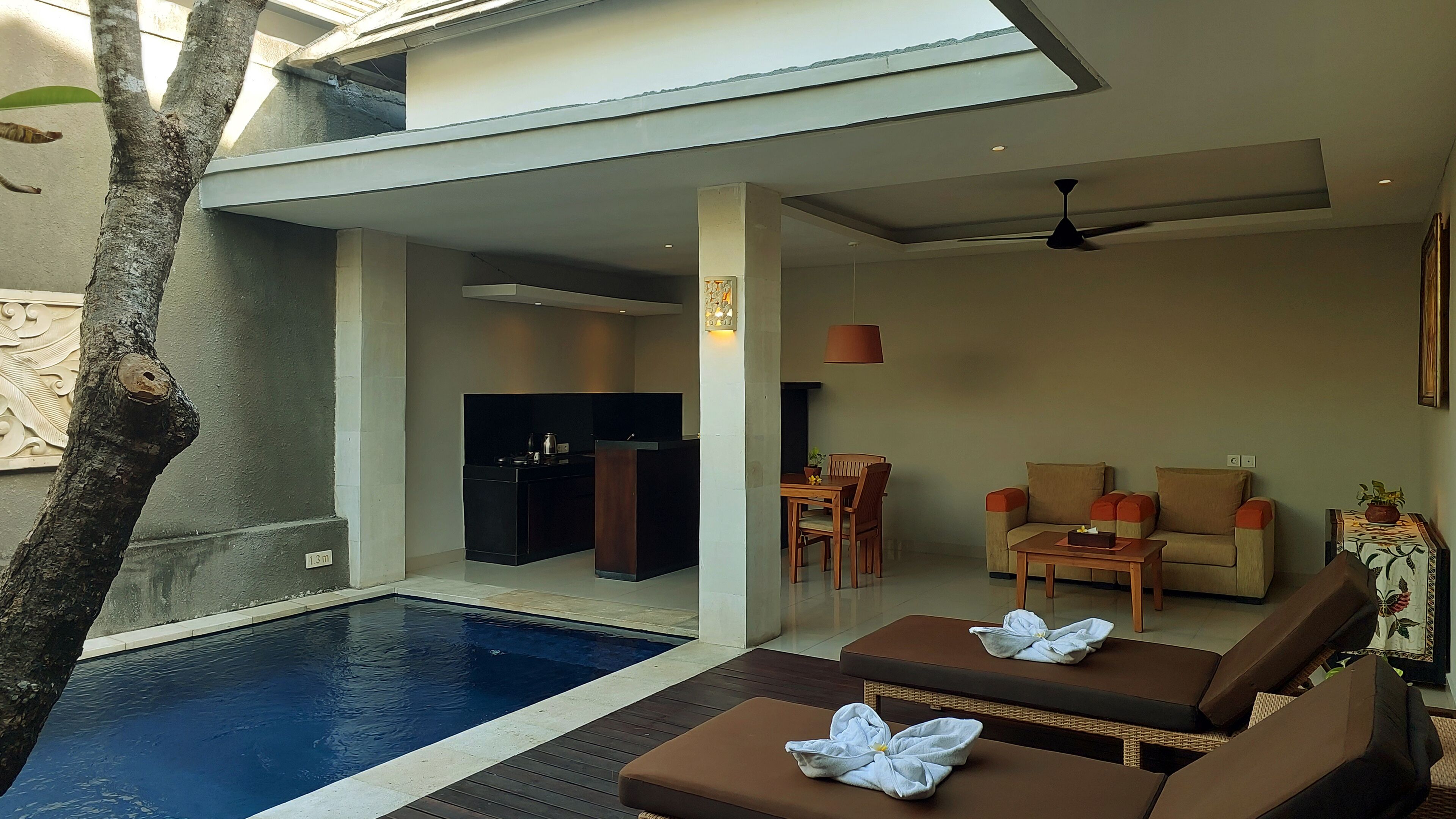 Un espace piscine intérieur moderne, doté de chaises longues et d’une table à manger.