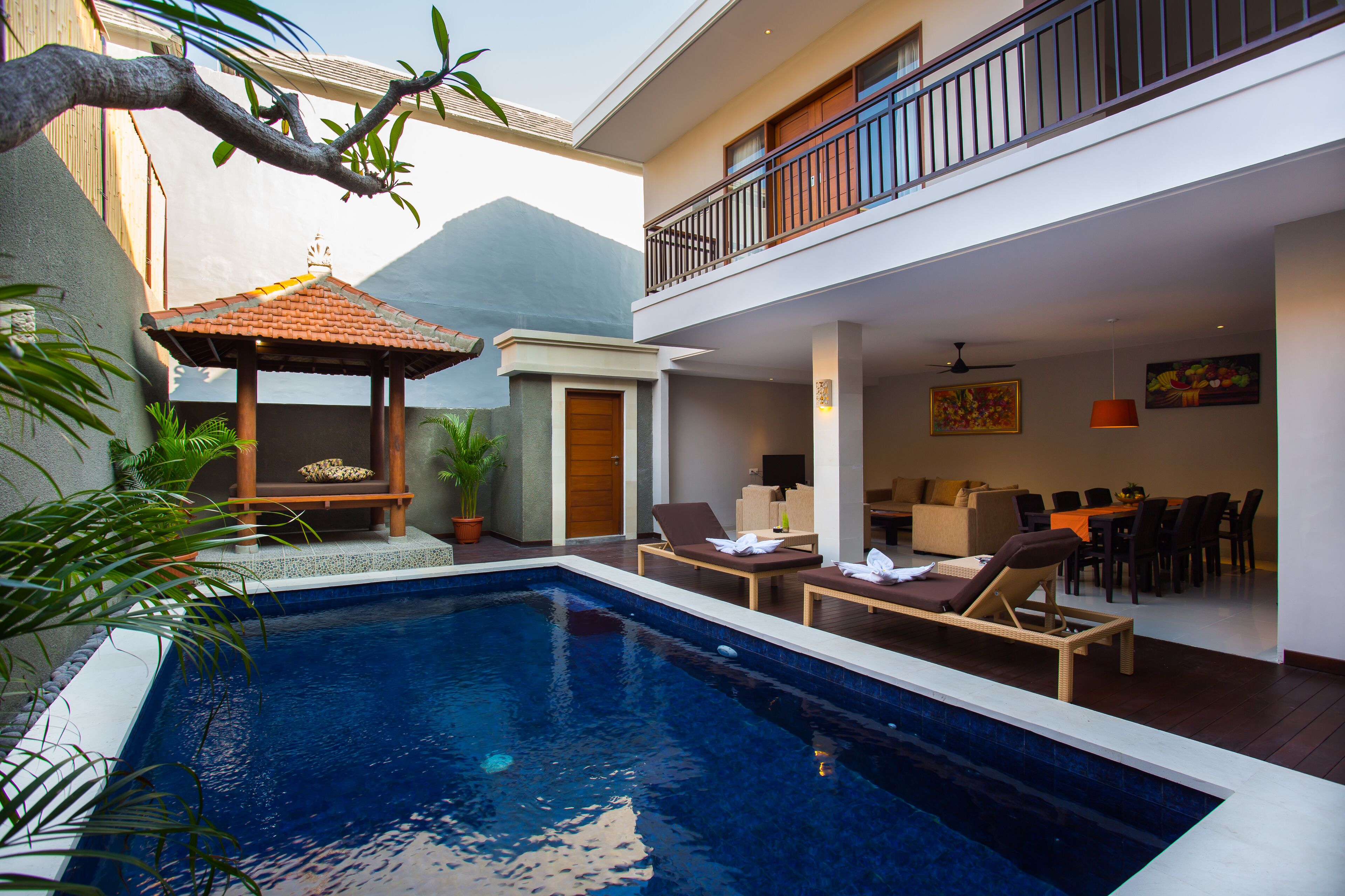 A pool area with lounge chairs, a small gazebo, and a dining area with a view of the mountain.