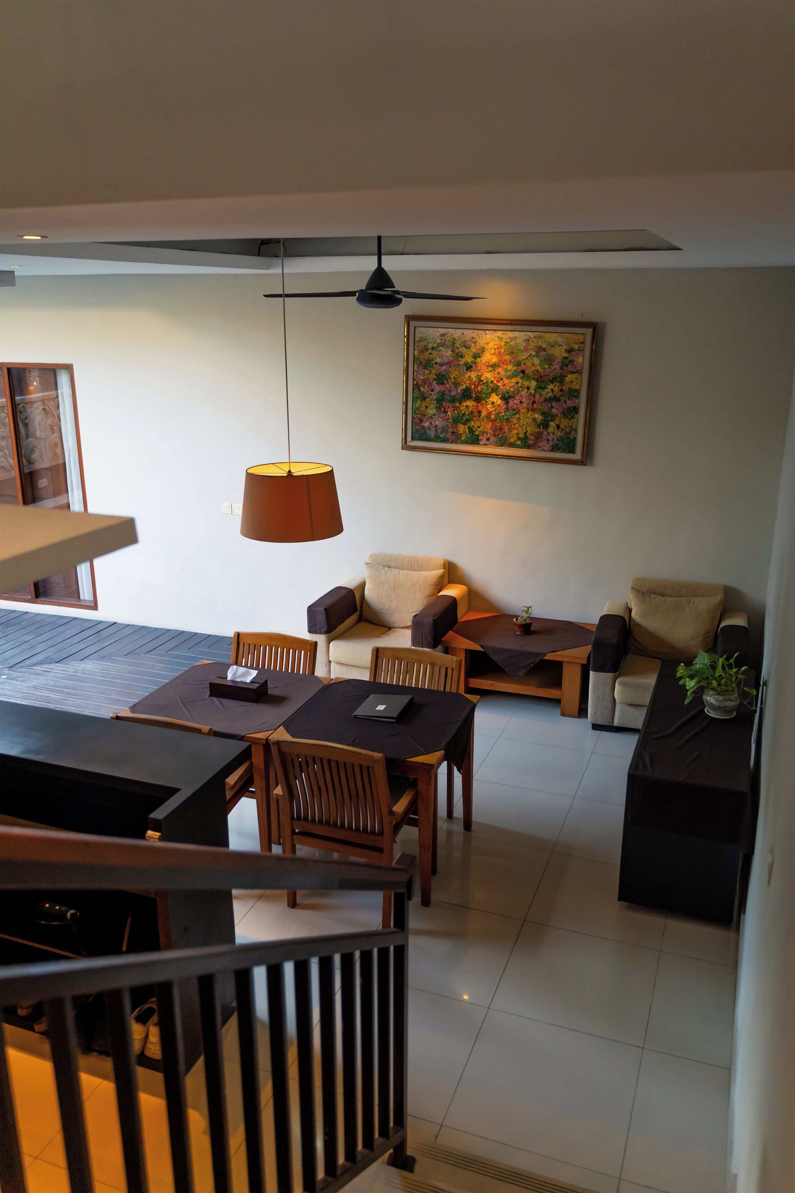 Una sala de estar moderna con comedor, que incluye un ventilador de techo, un cuadro y una planta en maceta.