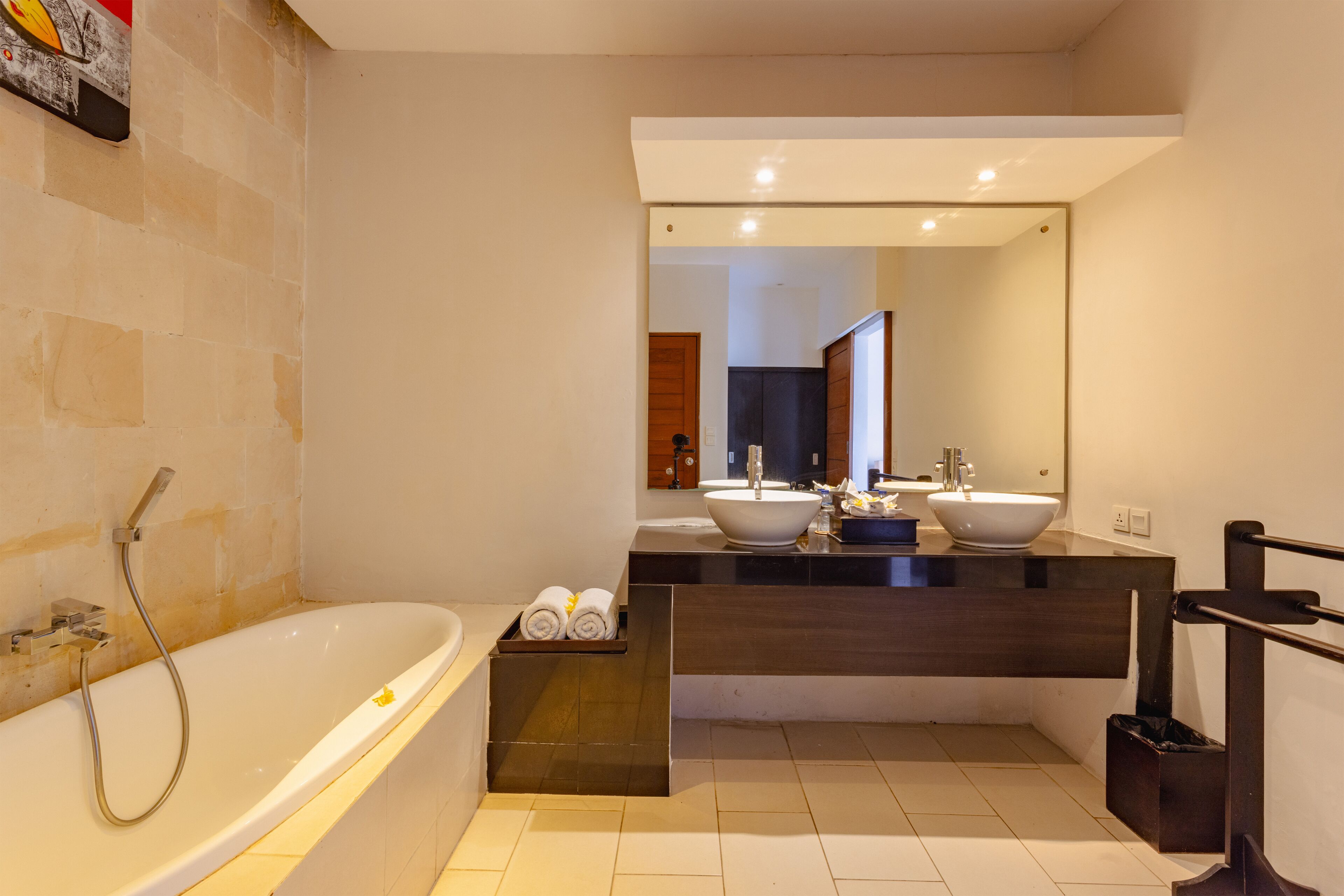 A modern bathroom with a large bathtub, two sinks, and a mirror above the vanity.