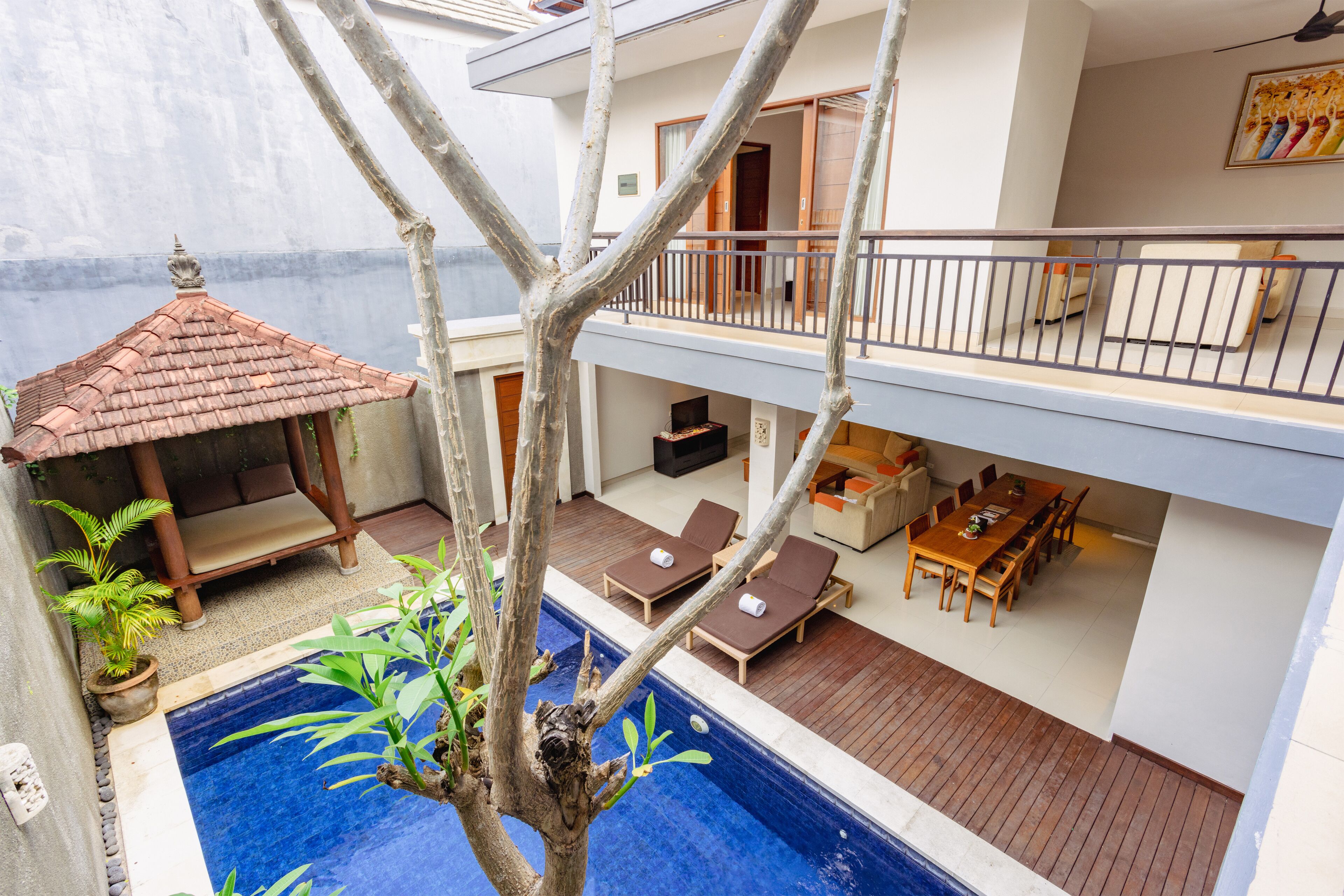 Um edifício de dois andares com piscina, espreguiçadeiras e área de refeições.