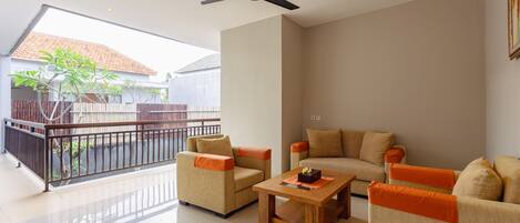 A spacious living area with a balcony, a ceiling fan, and a wooden coffee table.