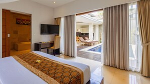 A hotel room with a bed, a desk, a TV, and a view of a pool and outdoor seating area. - The Light Exclusive Villas & SPA (Seminyak)
