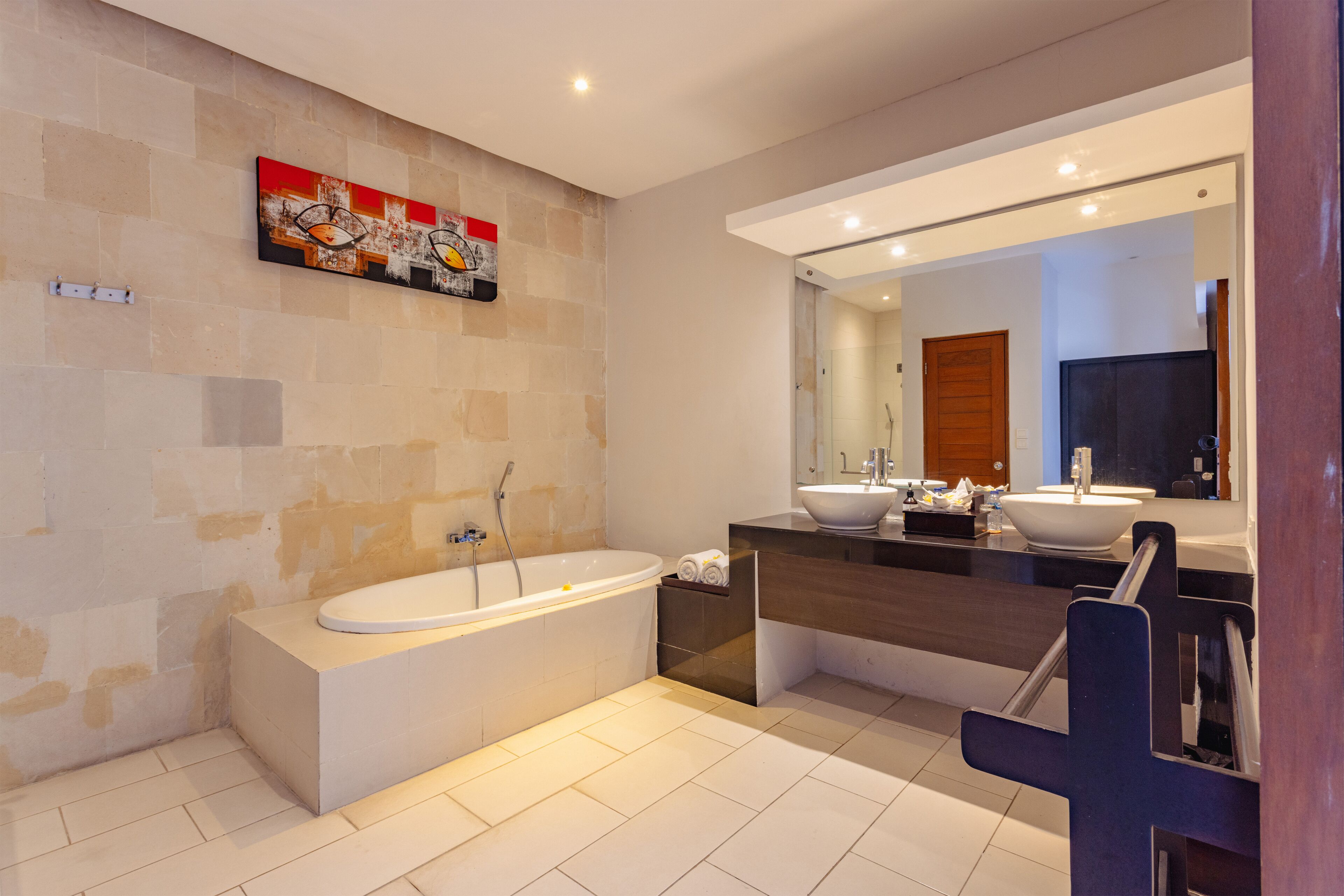 A modern bathroom with a freestanding bathtub, a large mirror, and a dark-toned vanity.