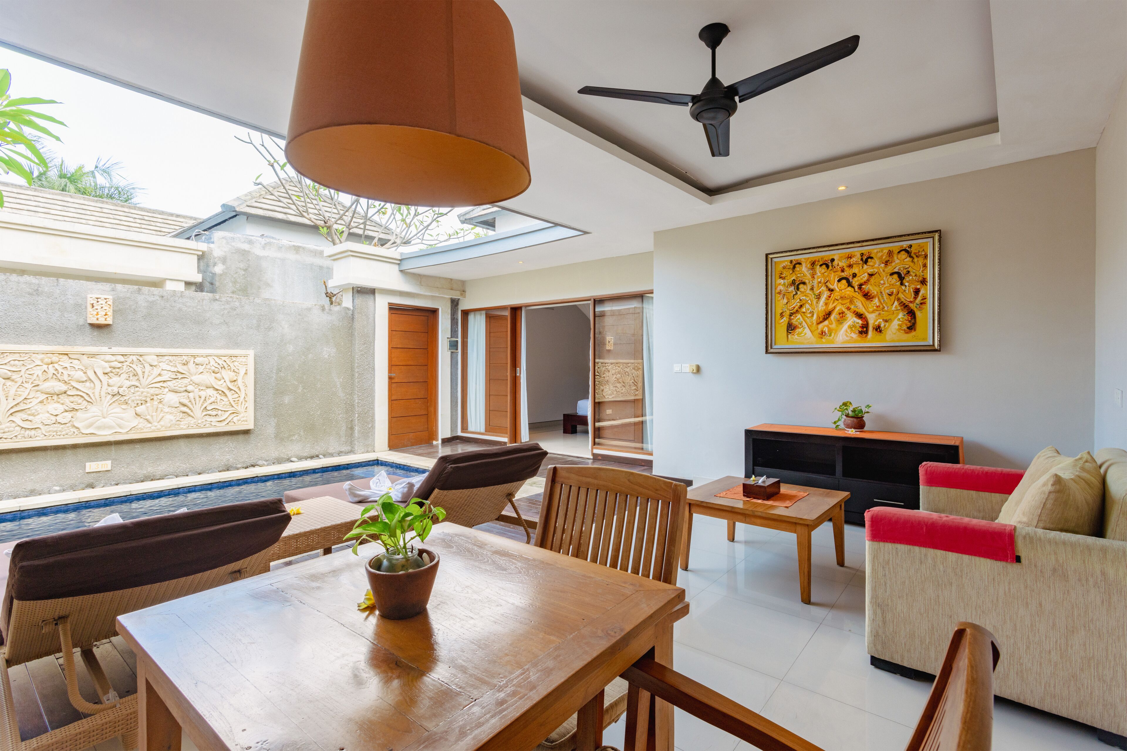 A spacious living area with a dining table, chairs, a sofa, and a ceiling fan.
