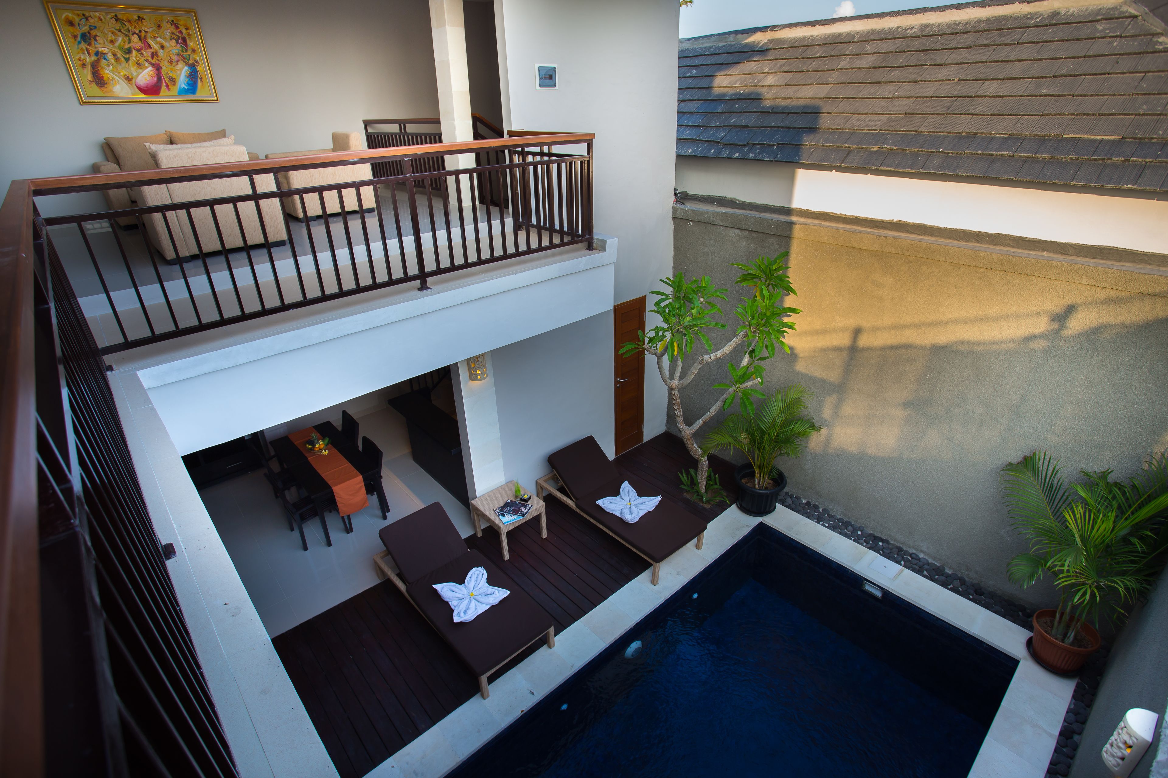 Un edificio de dos pisos con balcón, piscina y mobiliario de exterior.