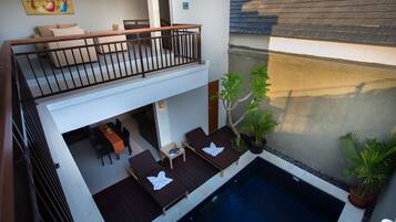 Un edificio de dos pisos con balcón, piscina y mobiliario de exterior.