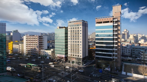 Un paisaje urbano con edificios modernos, incluyendo un hotel llamado "Golden City" con un letrero llamativo.