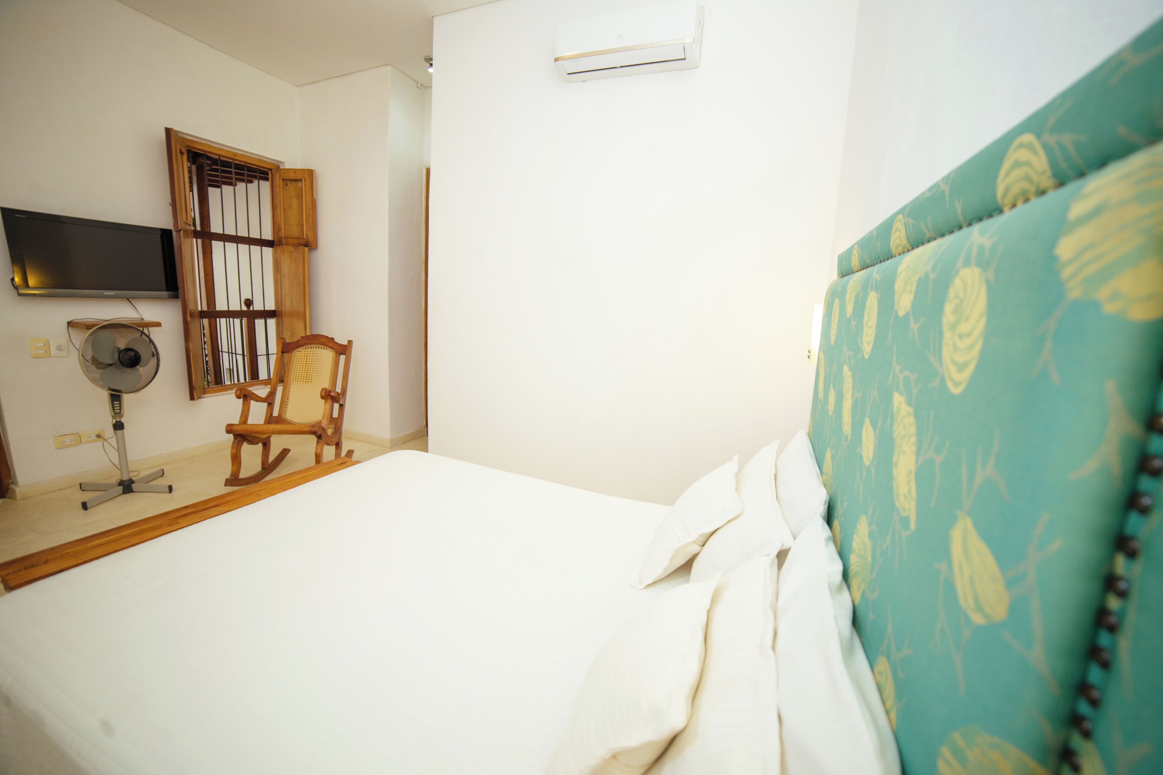 Een slaapkamer met een bed, een stoel, een televisie en een airconditioning.