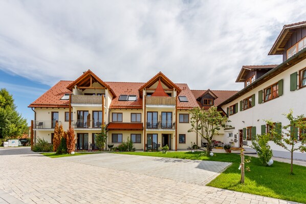 A multi-story building with balconies and a paved courtyard. - Landhotel und Gasthaus Wiedmann (Eresing)