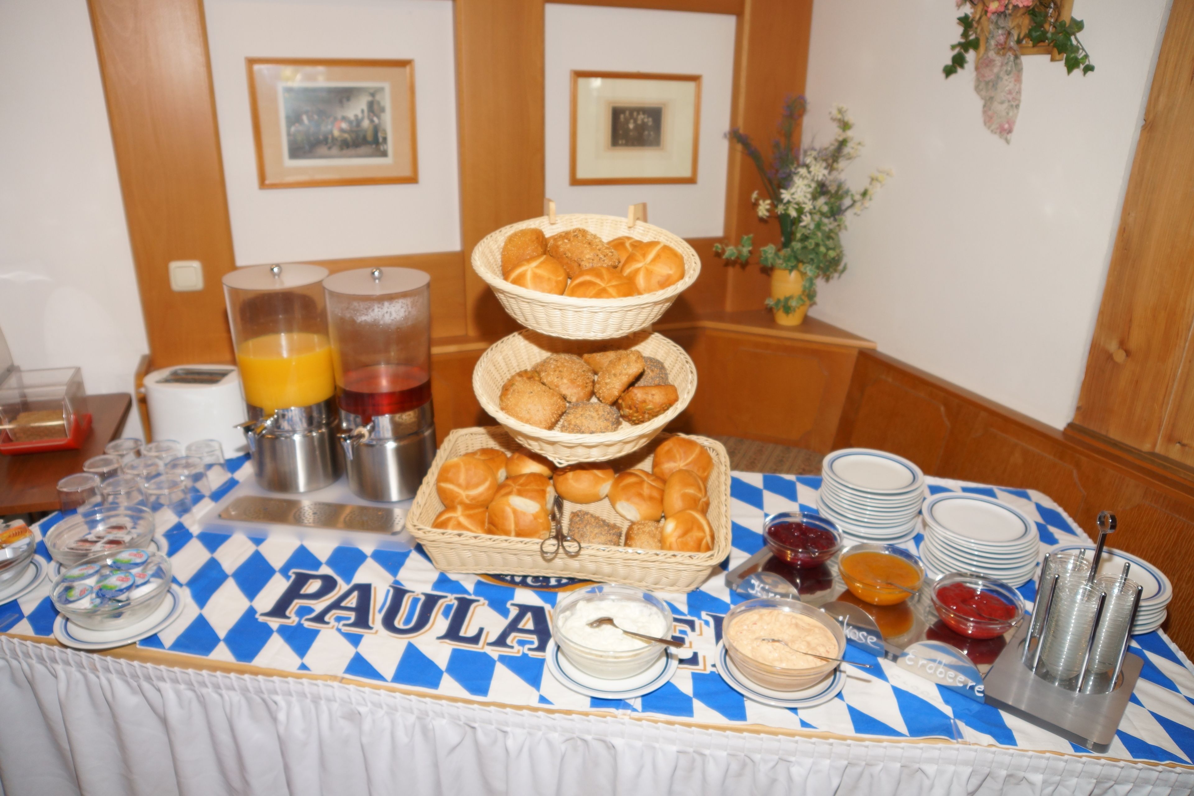 A breakfast buffet table with various food items and condiments, a coffee maker, and a fruit punch dispenser.