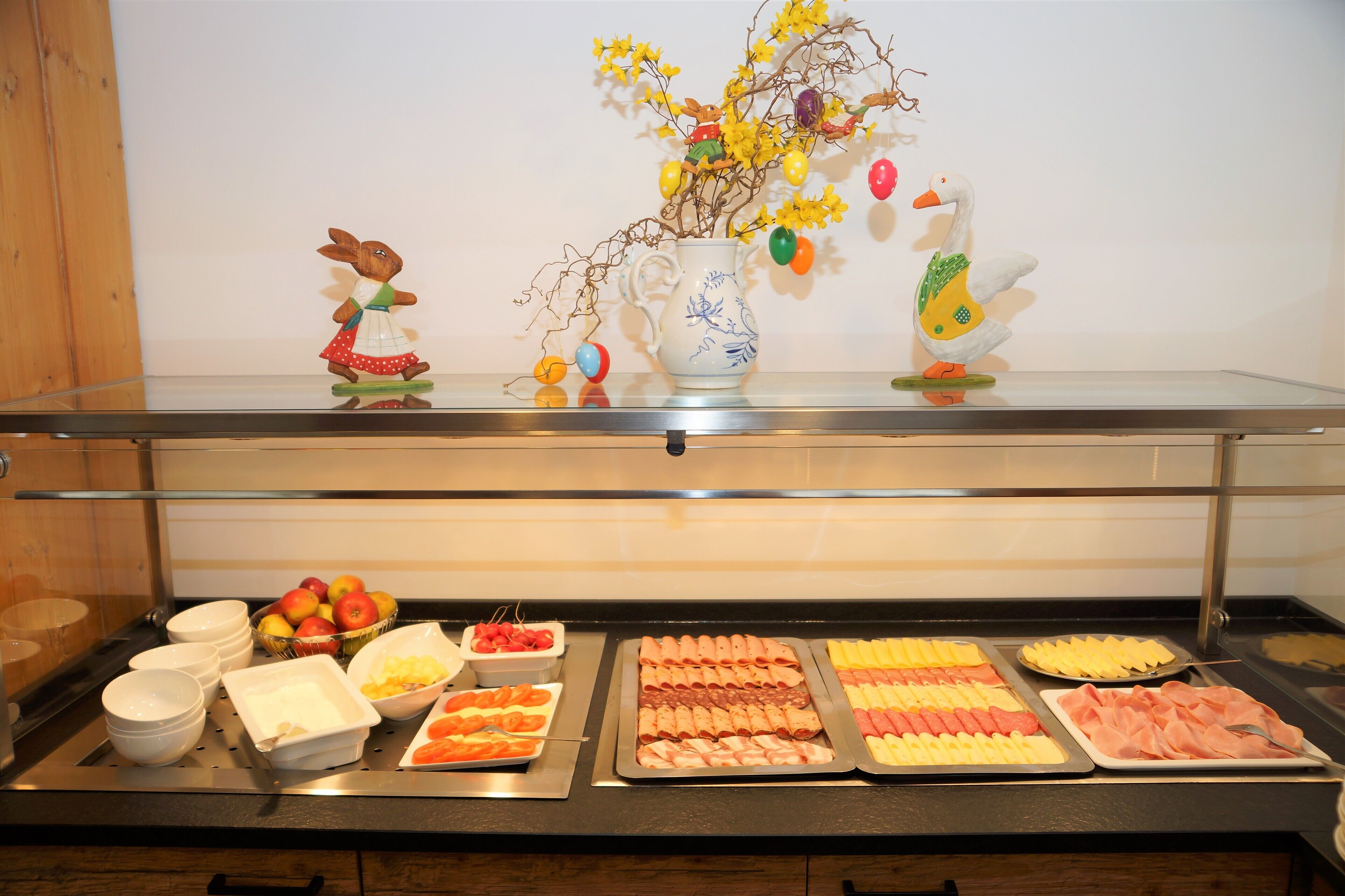 A buffet with various food items and a decorative display with figurines and a vase.