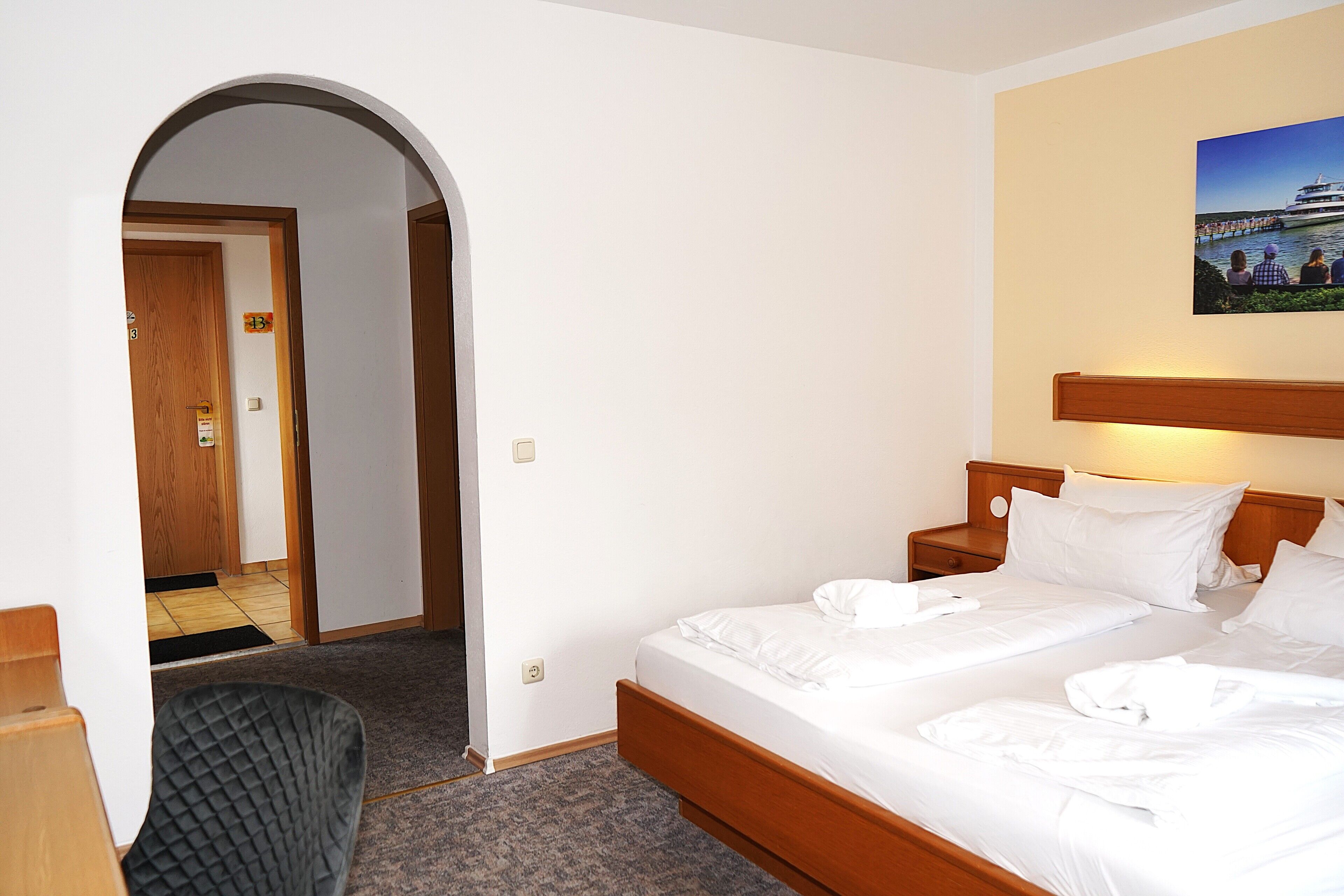 Ein Hotelzimmer mit Bett, Sessel, Nachttisch und einem Bild an der Wand.