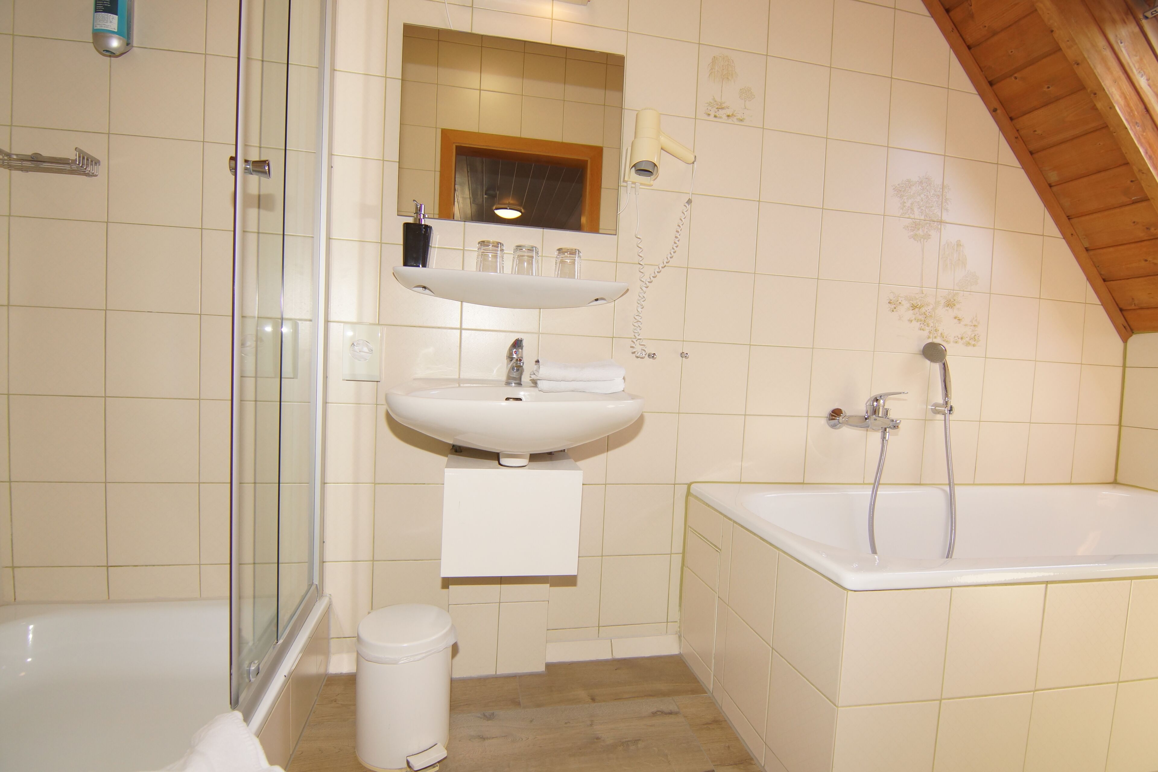 Un baño con bañera, lavamanos, cabina de ducha de vidrio y retrete.