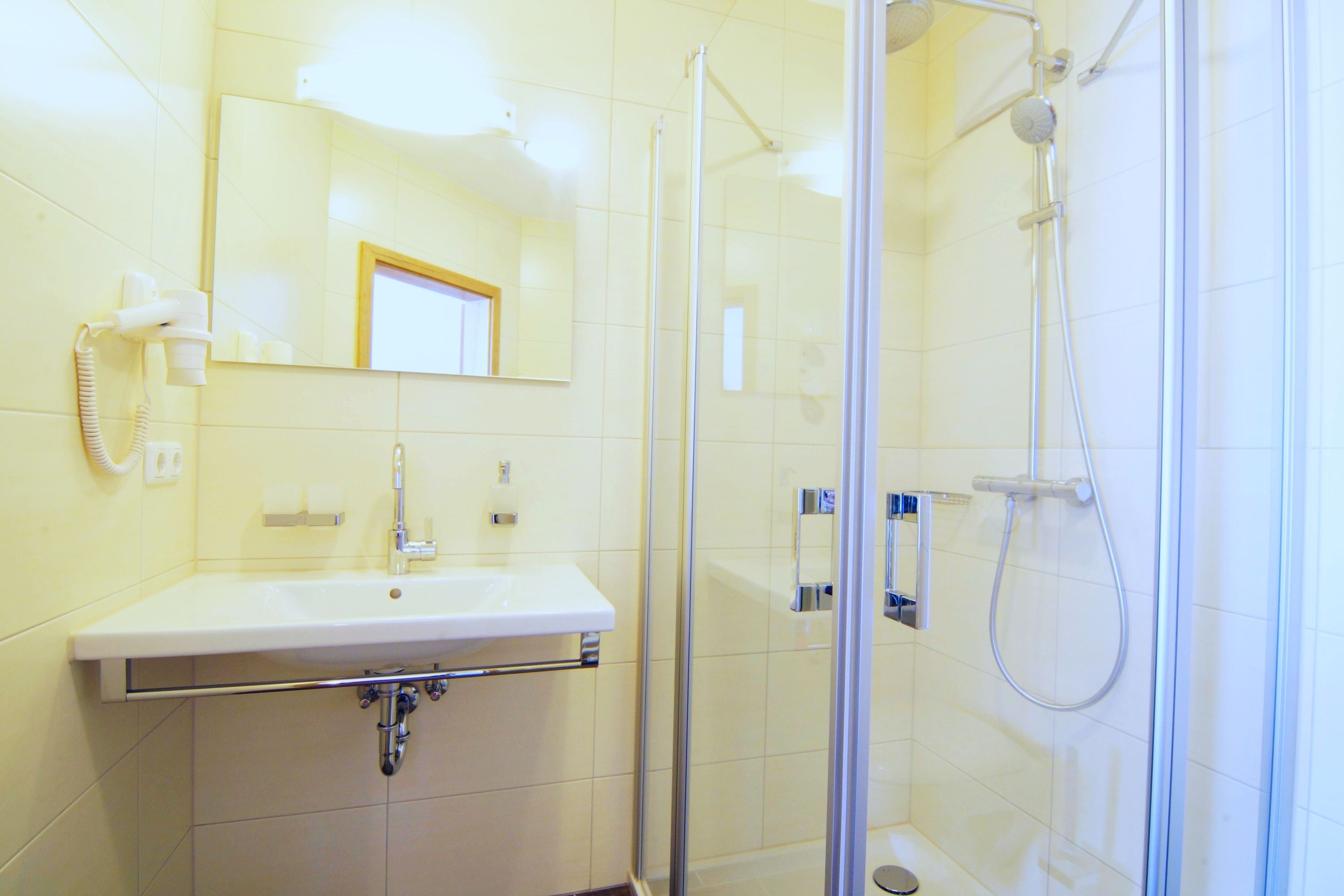 Une salle de bain équipée d’un lavabo, d’un miroir et d’une douche à parois de verre.